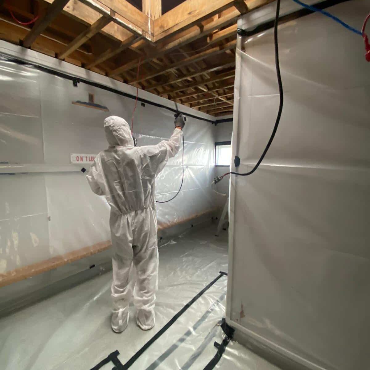 A worker in full safety suit and mask undertakes Class B Asbestos removal