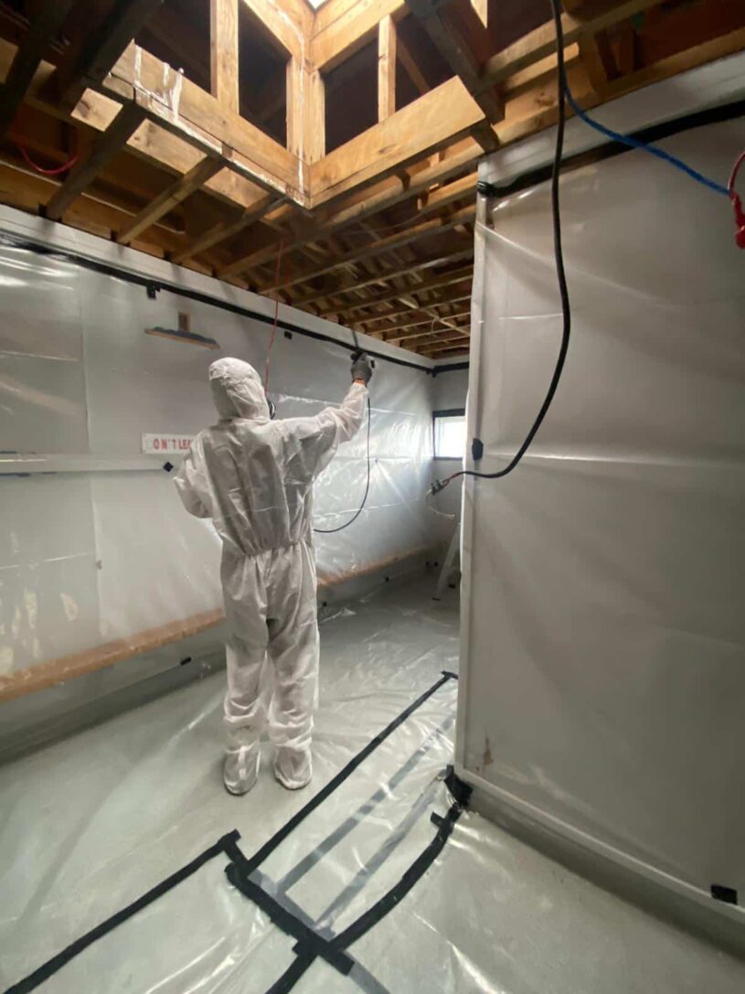 A worker in full safety suit and mask undertakes Class B Asbestos removal