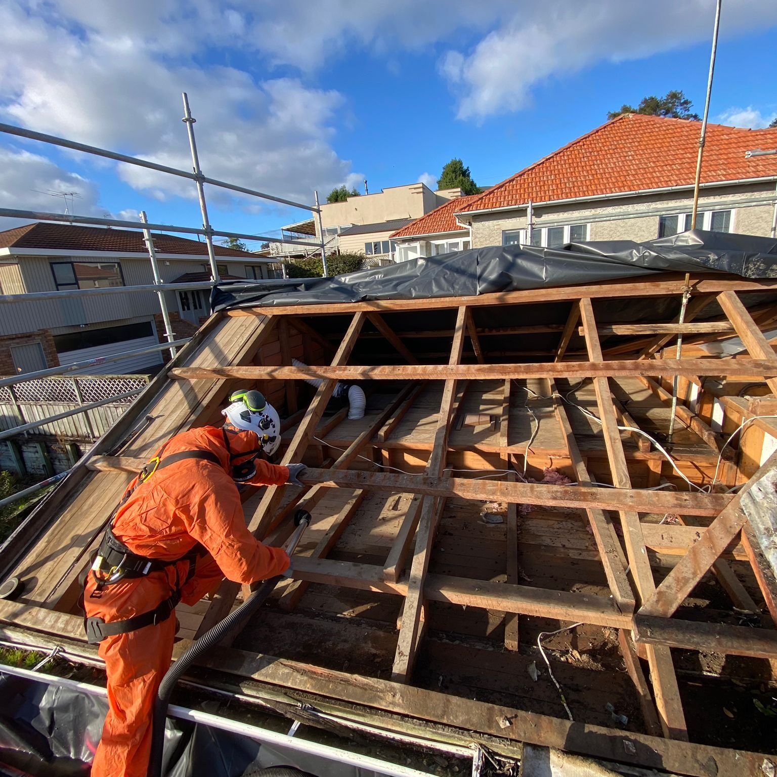 An asbestos removal expert in full safety gear working on a Class B Asbestos roof removal project in Auckland.