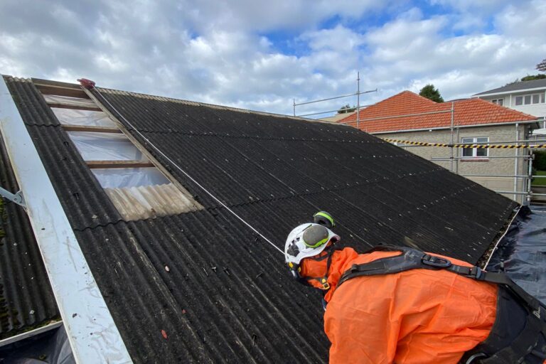 A asbestos removal worker in safety gear working on a Class B Asbestos roof removal